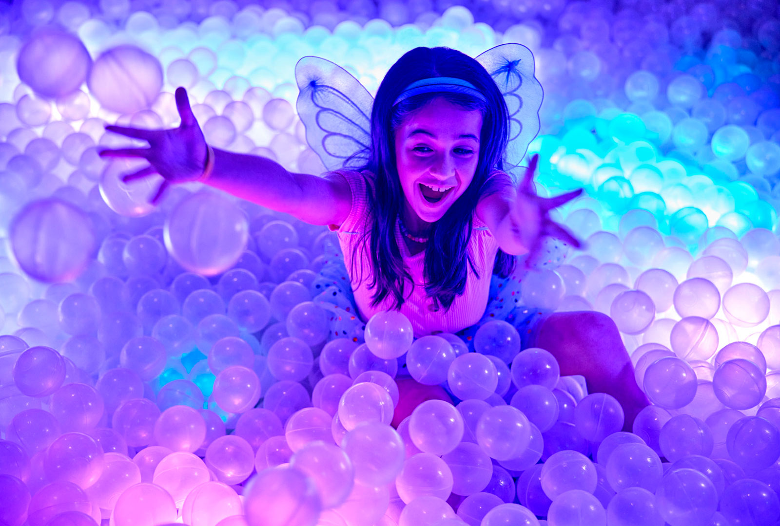 a girl in a ball pit with a butterfly wings